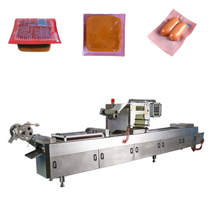 Thermoforming vacuum packaging machine for industrial food and product sealing with continuous forming and cutting.
